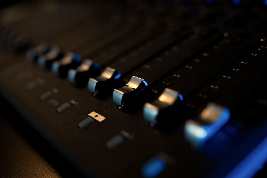 Faders of a mixing controller in low blue light.